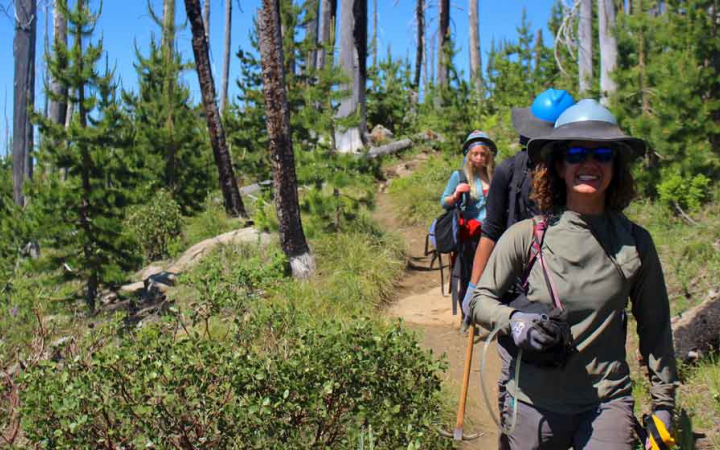 a group of students smile as they walk along a trail to work on a service project